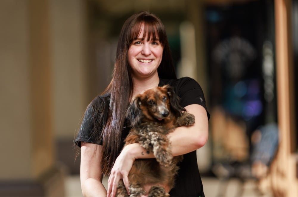 a vet staff embraces a small dog in her arms